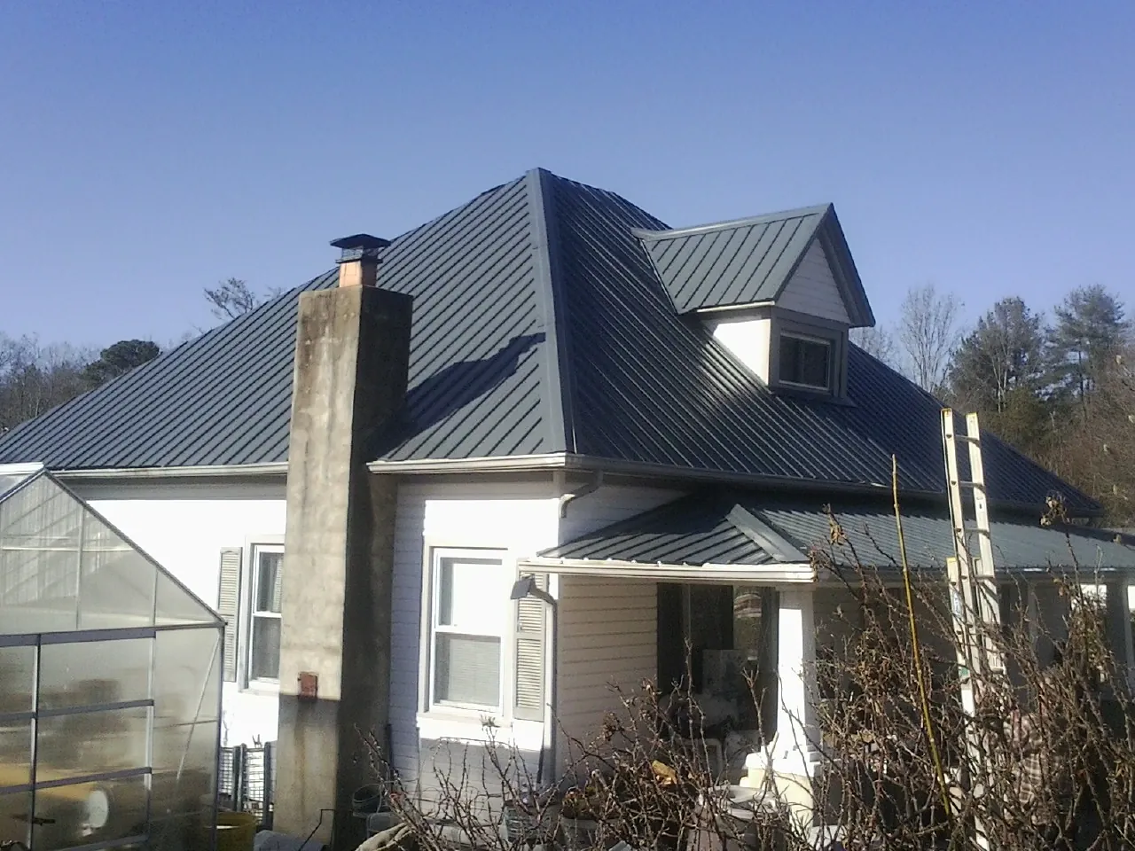 Dark blue standing seam metal roof on a white farmhouse with dormer — Slate & Tile Roof Repair by Roofing Brothers in Winthrop